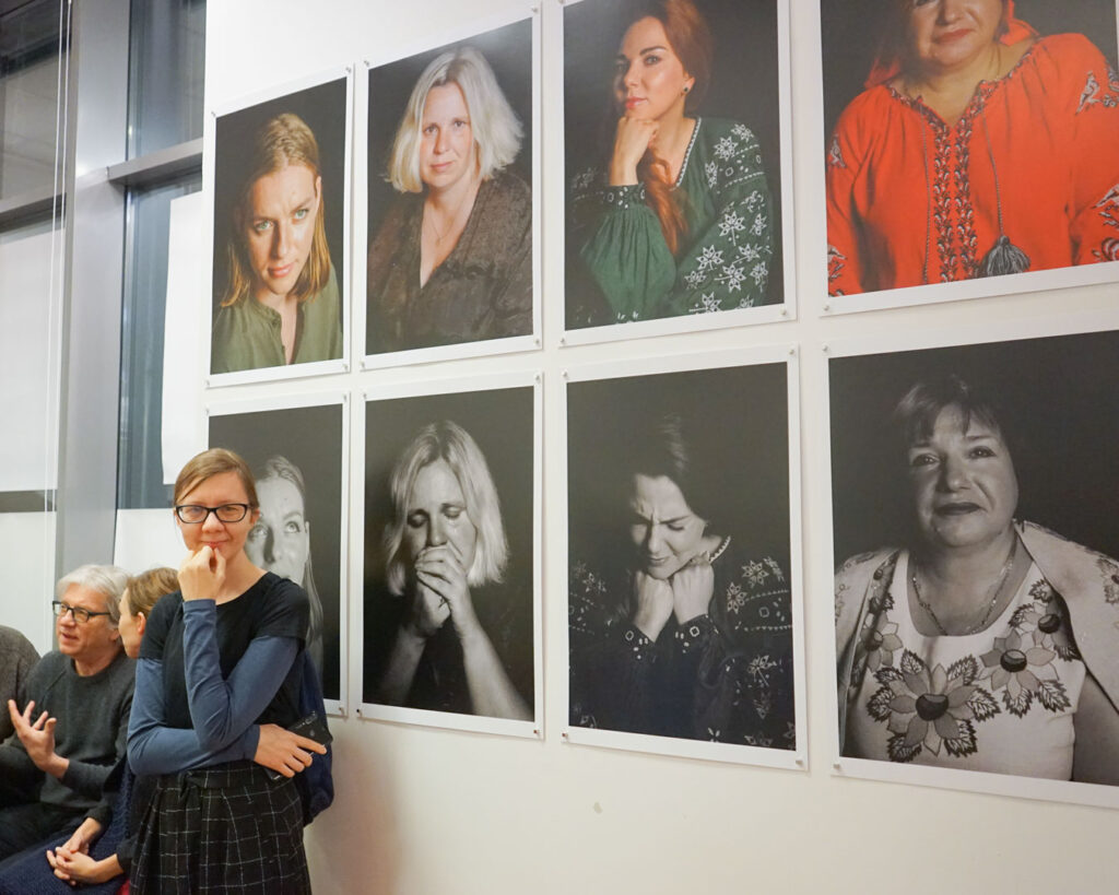 Goście wystawy oglądają fotografie portretowe ukraińskich kobiet prezentowane w sali.